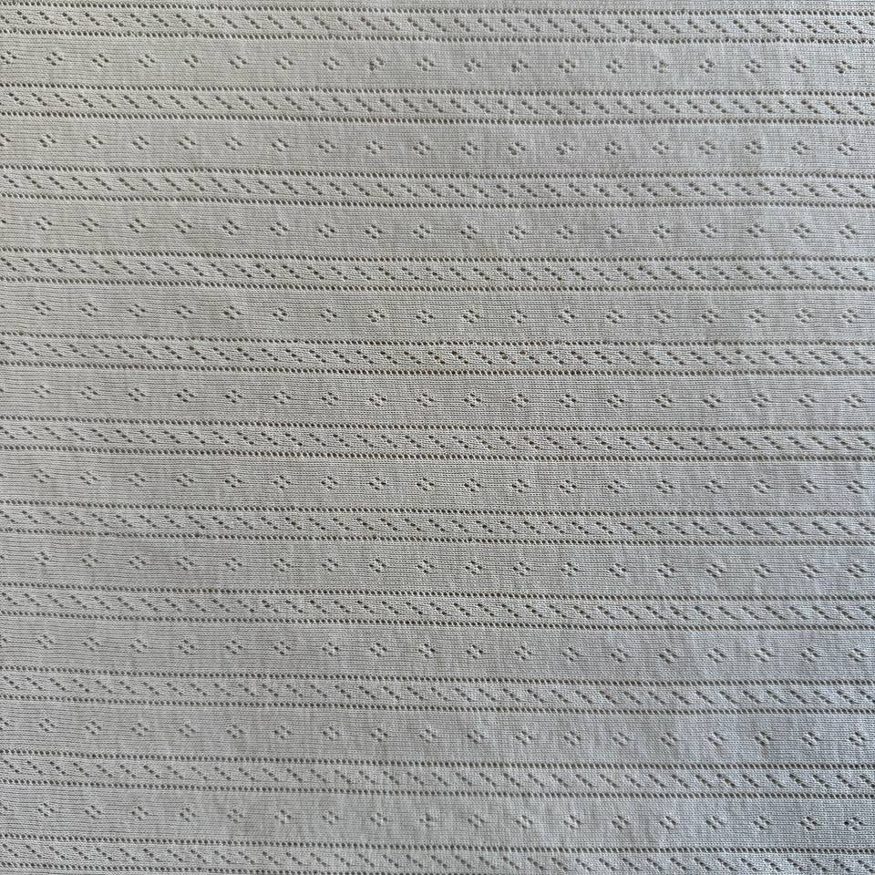Soft cream cotton pointelle knit fabric with delicate textured pattern