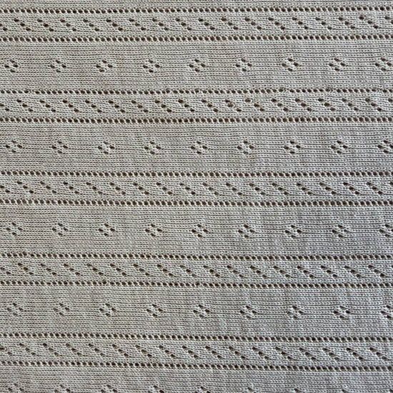 Soft cream cotton pointelle knit fabric with delicate textured pattern