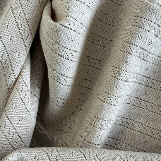 Soft cream cotton pointelle knit fabric with delicate textured pattern