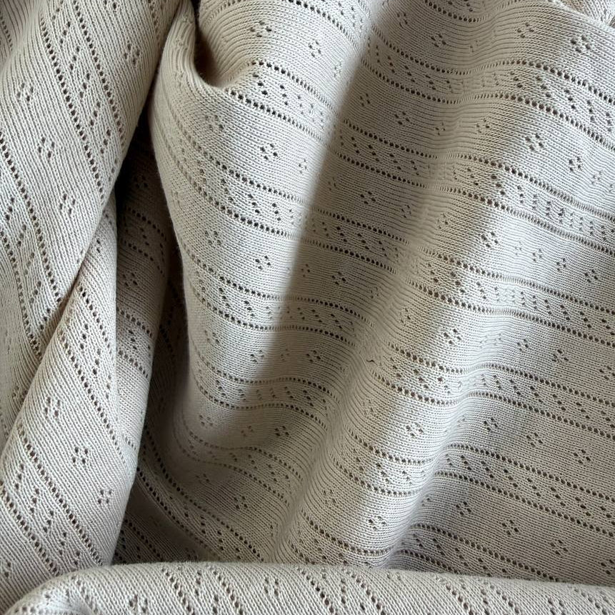 Soft cream cotton pointelle knit fabric with delicate textured pattern
