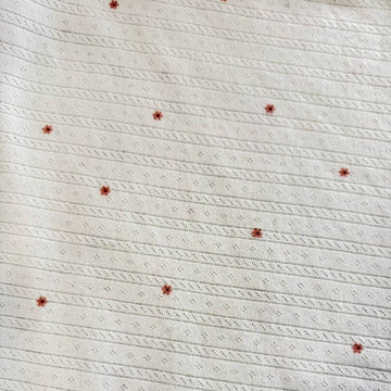 White cotton pointelle knit fabric with small floral print and delicate texture