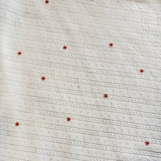 White cotton pointelle knit fabric with small floral print and delicate texture
