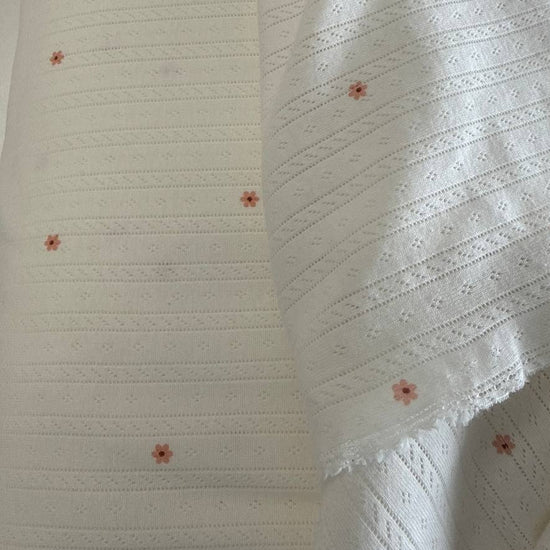 White cotton pointelle knit fabric with small floral print and delicate texture