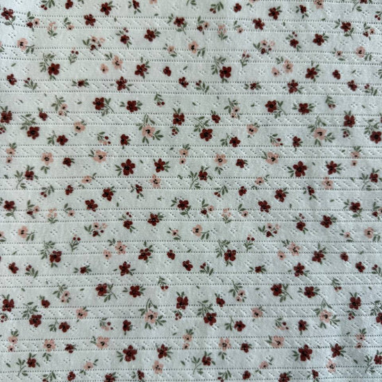 White cotton pointelle knit fabric with vintage floral print and delicate texture