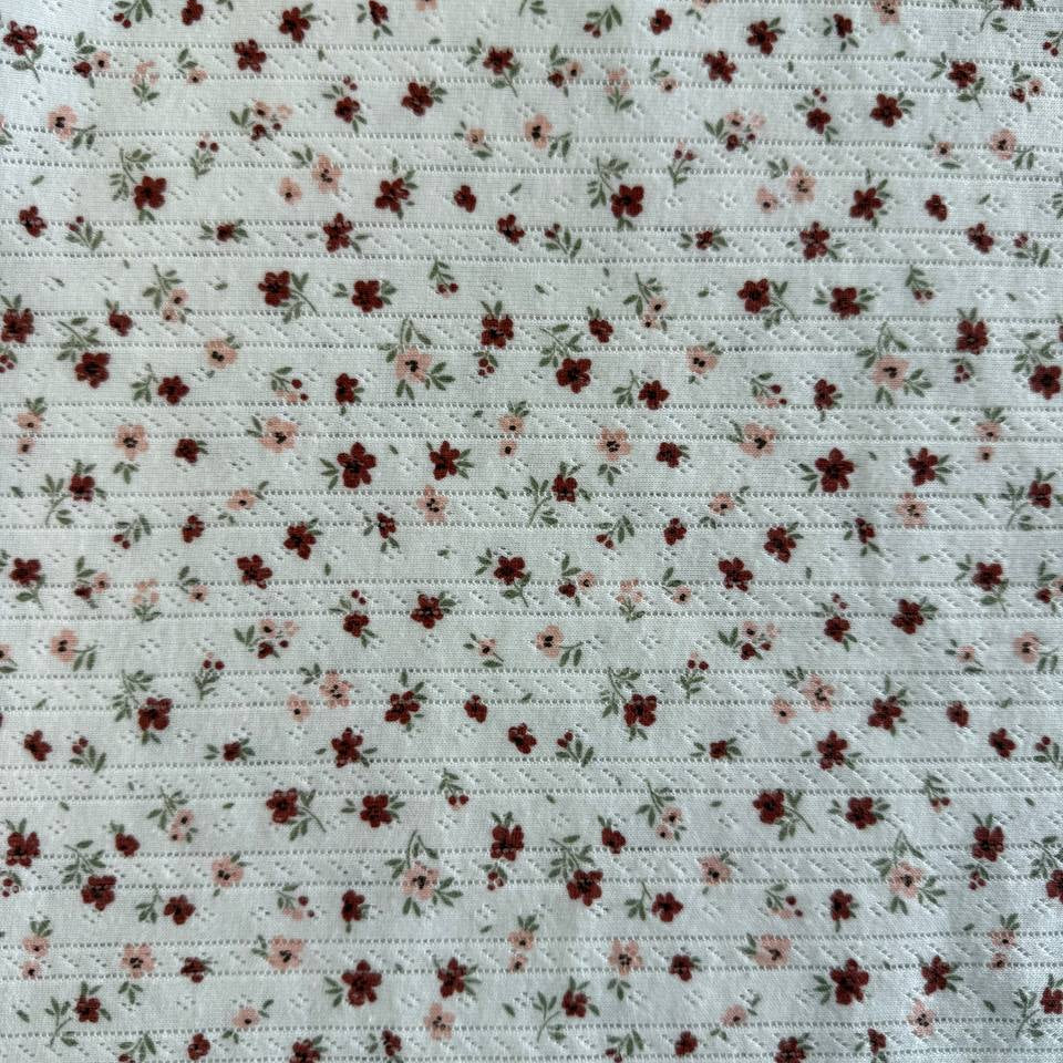 White cotton pointelle knit fabric with vintage floral print and delicate texture