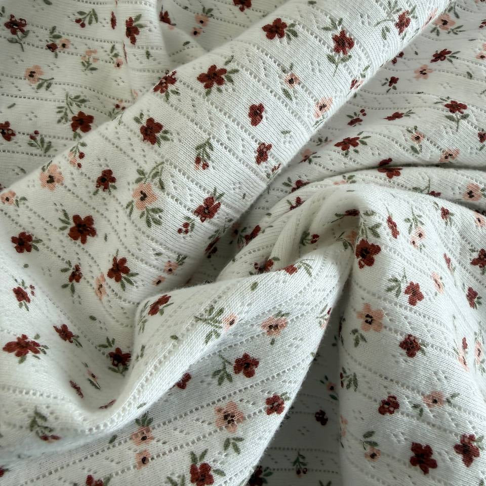 White cotton pointelle knit fabric with vintage floral print and delicate texture