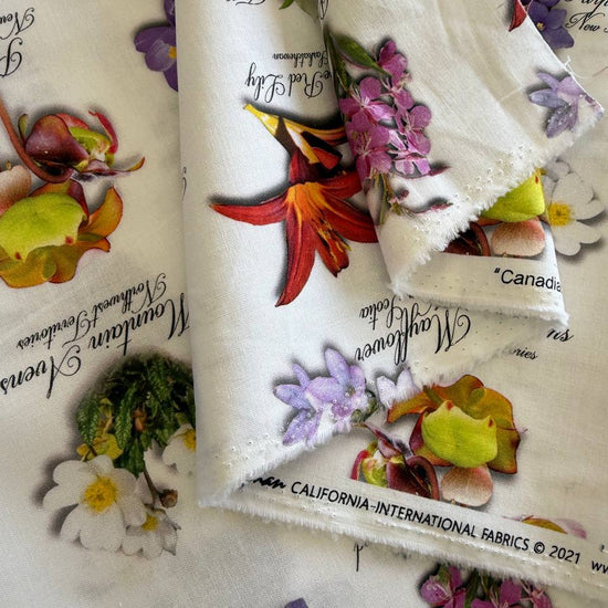 White cotton fabric with colorful botanical flower print and handwritten names from Canadian Road Trip collection by Hoffman