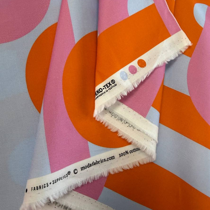 Retro geometric cotton fabric with bold pink and orange interlocking lines on a light blue background from Groove by Emily Van Hoff for Moda.