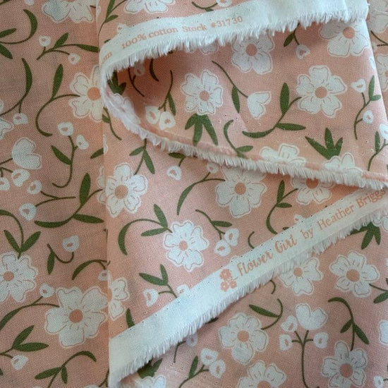 Blush pink cotton fabric with small white flowers and green stems from Flower Girl collection by Sew Quilty Life for Moda