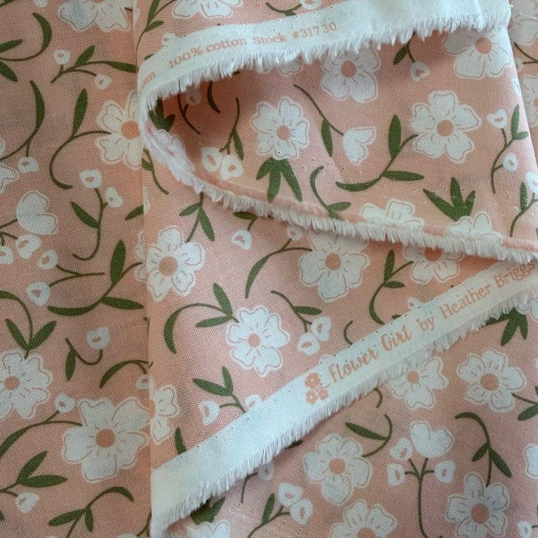 Blush pink cotton fabric with small white flowers and green stems from Flower Girl collection by Sew Quilty Life for Moda
