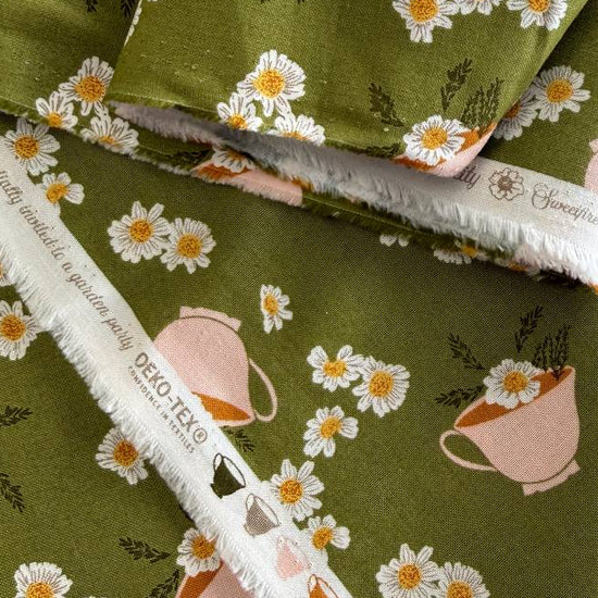 Frivolity cotton fabric with daisies and teacups in green and blush tones