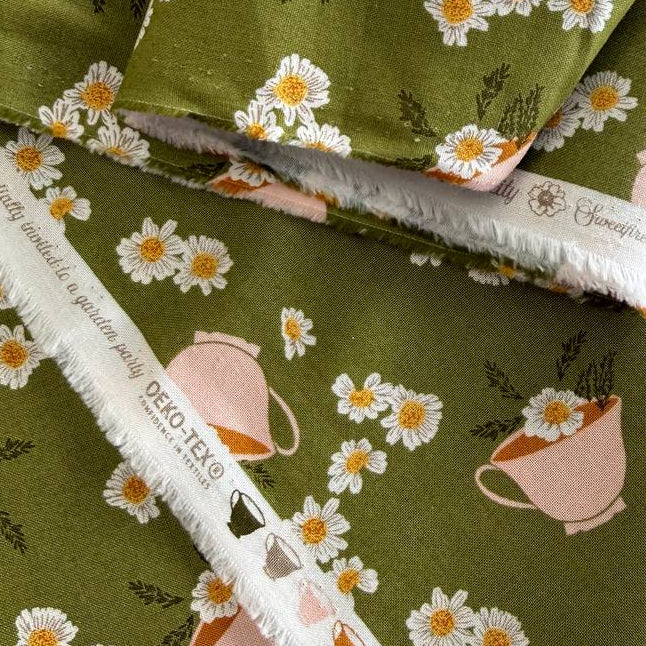Frivolity cotton fabric with daisies and teacups in green and blush tones