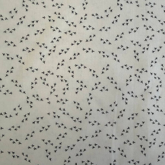 Cream cotton fabric with small black bird footprint pattern from The Henhouse collection by Gingiber for Moda