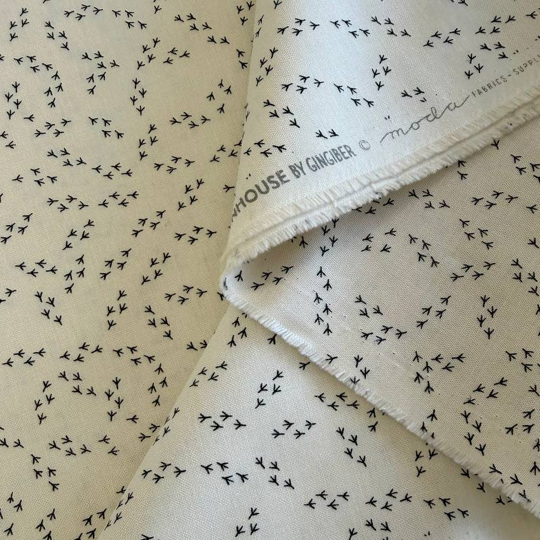 Cream cotton fabric with small black bird footprint pattern from The Henhouse collection by Gingiber for Moda