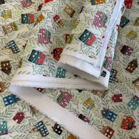 Paper Hamlet fabric by Moda with colorful houses on a light green leafy background