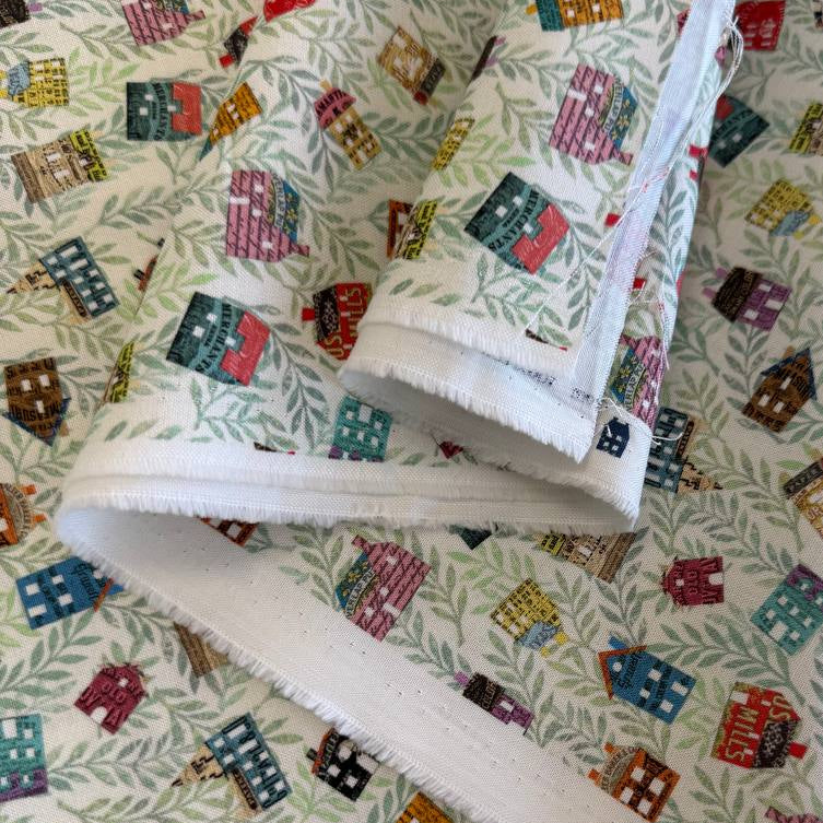 Paper Hamlet fabric by Moda with colorful houses on a light green leafy background