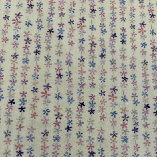 Pastel floral cotton fabric with small purple blue and pink flowers on cream background