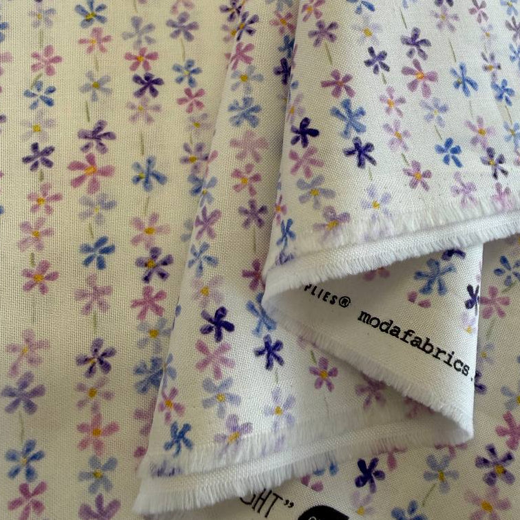 Pastel floral cotton fabric with small purple blue and pink flowers on cream background