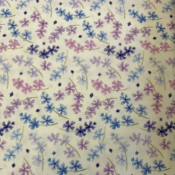 Scattered pastel floral cotton fabric with purple blue and pink flowers on soft cream background