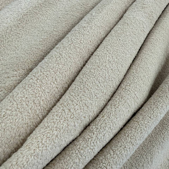 This cozy fireside sherpa fleece features a plush, curly texture with an ultra-soft hand feel and a warm, natural beige tone.