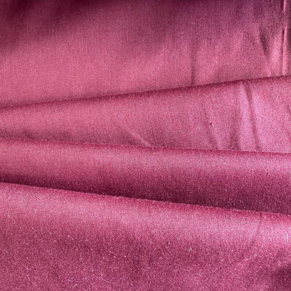Smooth solid broadcloth fabric with a crisp hand feel and durable structure.