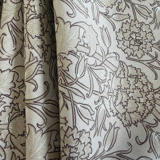 Wide cotton sheeting fabric with beige and brown floral pattern folded on bolt 