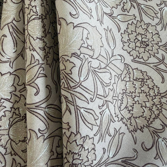 Wide cotton sheeting fabric with beige and brown floral pattern folded on bolt 