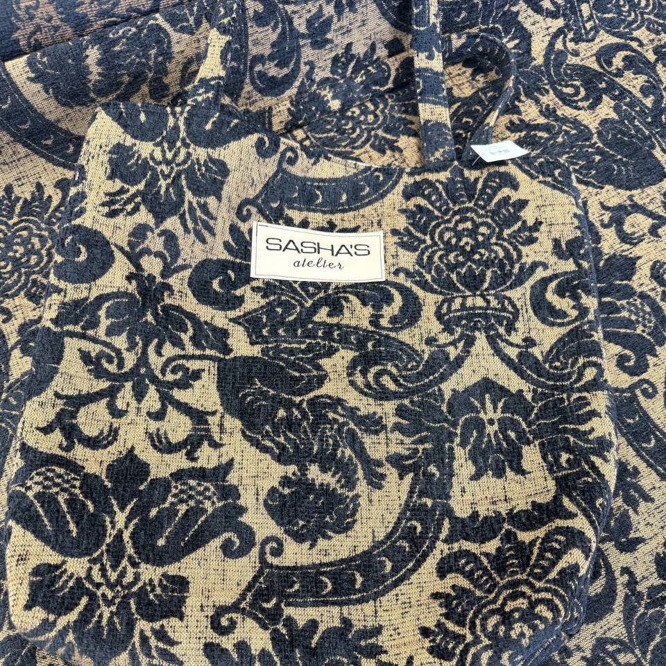 Black and beige woven upholstery fabric with an elegant floral ornamental pattern, used for handmade Sasha’s Atelier bags, cushions, upholstery, and home décor.