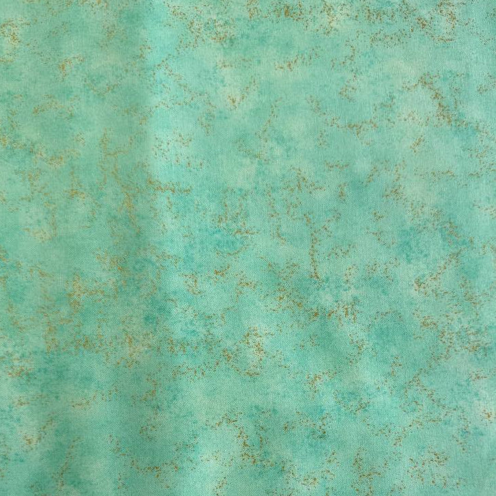 Stack of Northcott Shimmer Basics speckled quilting cotton fabrics in pastel shades with subtle metallic shimmer.