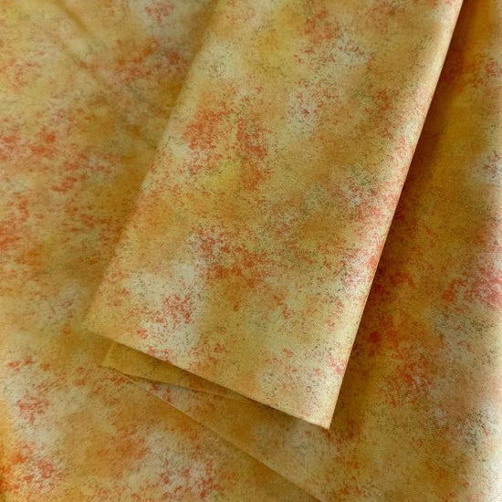 Stack of Northcott Shimmer Basics speckled quilting cotton fabrics in pastel shades with subtle metallic shimmer.