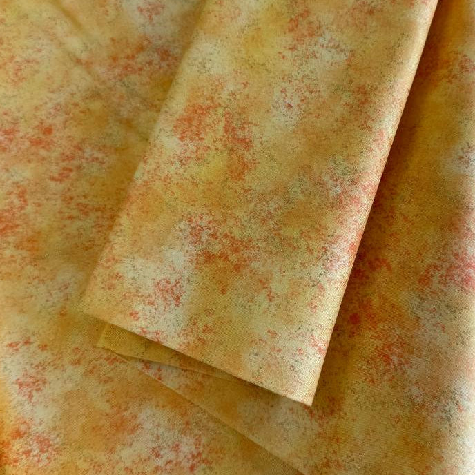 Stack of Northcott Shimmer Basics speckled quilting cotton fabrics in pastel shades with subtle metallic shimmer.