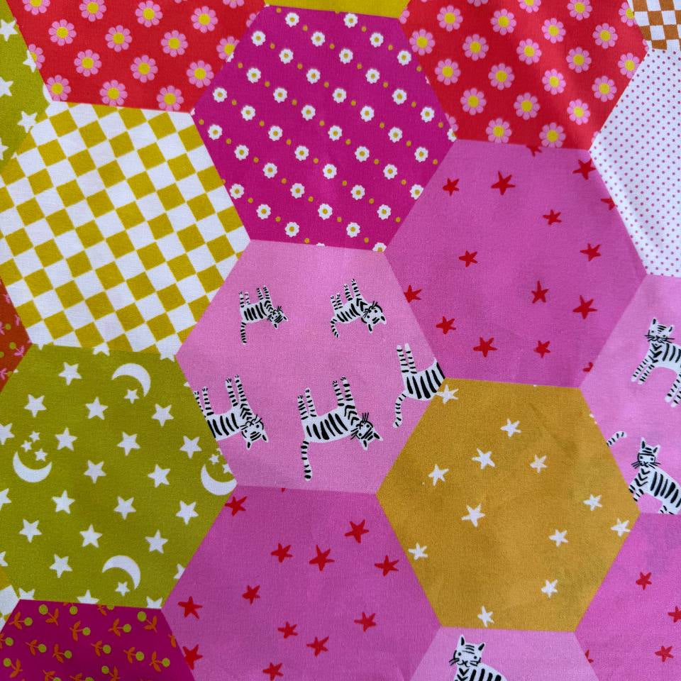 Colorful Ruby Star Society Catnap wide backing fabric with bright hexagon patchwork print featuring florals, stars, moons, and playful animal motifs.