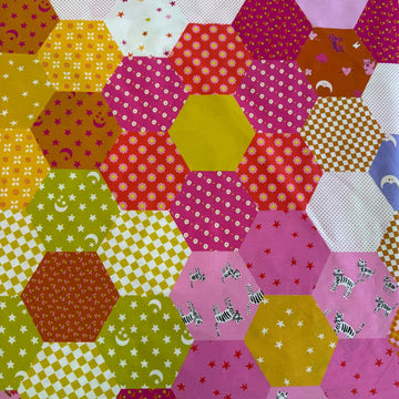 Colorful Ruby Star Society Catnap wide backing fabric with bright hexagon patchwork print featuring florals, stars, moons, and playful animal motifs.