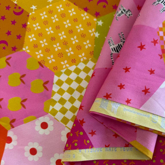 Colorful Ruby Star Society Catnap wide backing fabric with bright hexagon patchwork print featuring florals, stars, moons, and playful animal motifs.
