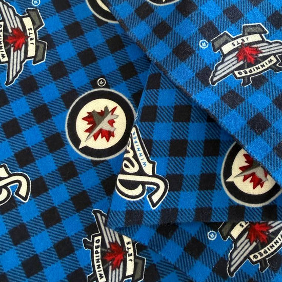 Winnipeg Jets NHL cotton flannel fabric with official team logos on a blue and black checkered background.