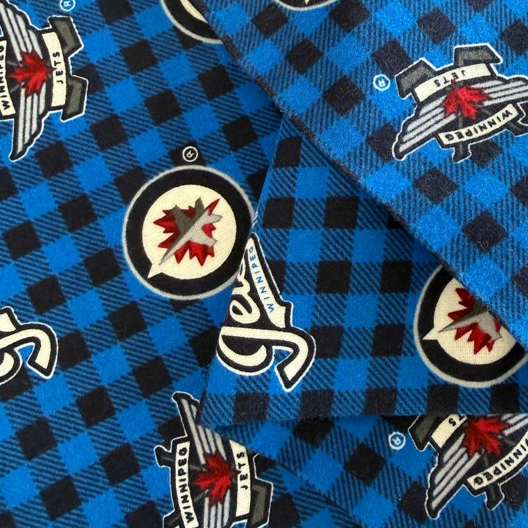 Winnipeg Jets NHL cotton flannel fabric with official team logos on a blue and black checkered background.