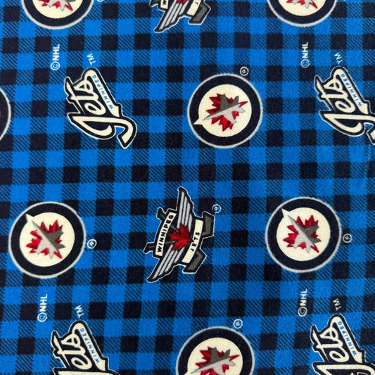 Winnipeg Jets NHL cotton flannel fabric with official team logos on a blue and black checkered background.