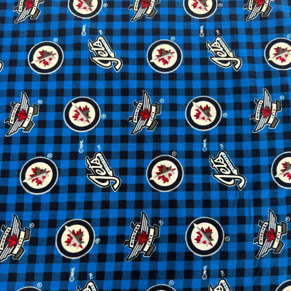 Winnipeg Jets NHL cotton flannel fabric with official team logos on a blue and black checkered background.