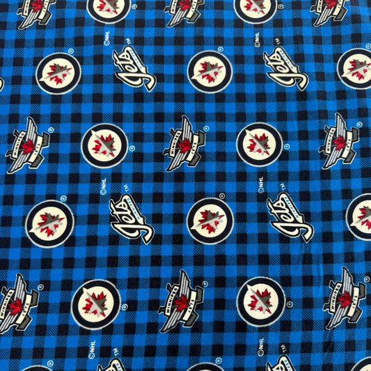Winnipeg Jets NHL cotton flannel fabric with official team logos on a blue and black checkered background.