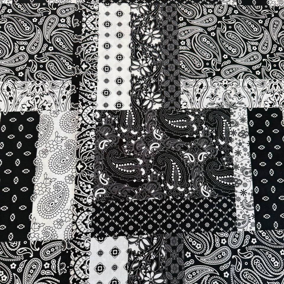 Quilting cotton fabric featuring a patchwork collage of paisley, floral, geometric, and bandana-inspired patterns arranged in contrasting blocks.