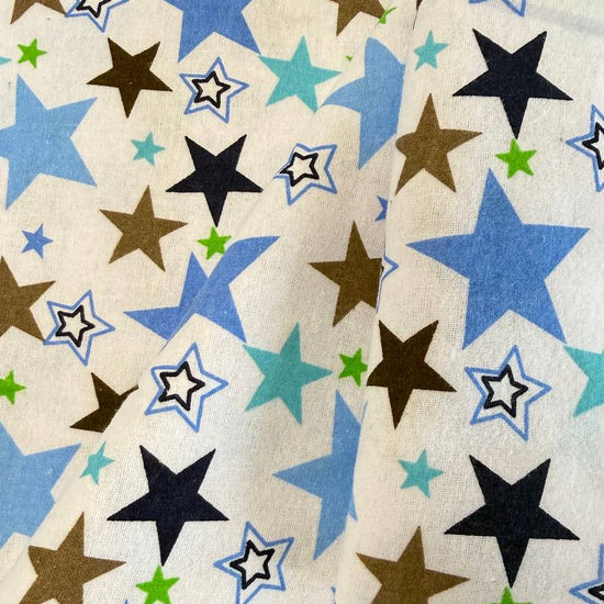 White flannelette fabric with blue, brown, navy, and green star print on a soft cotton blend background.