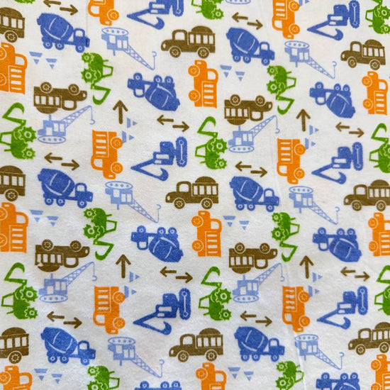 White flannelette fabric featuring colorful construction vehicles including dump trucks, excavators, cranes, and cement mixers in blue, orange, green, and brown.