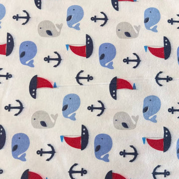 White flannelette fabric featuring blue and grey whales, red sailboats, and navy anchors in a playful nautical pattern.