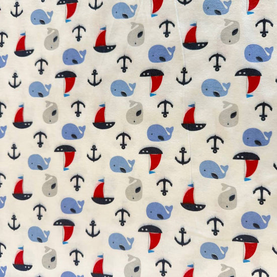White flannelette fabric featuring blue and grey whales, red sailboats, and navy anchors in a playful nautical pattern.