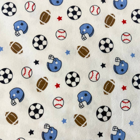 White flannelette fabric featuring soccer balls, baseballs, footballs, blue helmets, and stars in a playful sports-themed pattern.
