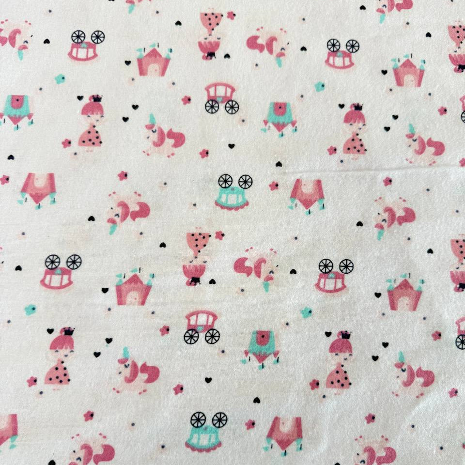 Soft white flannelette fabric featuring pink princesses, unicorns, castles, carriages, dresses, and crowns in a whimsical fairytale print.