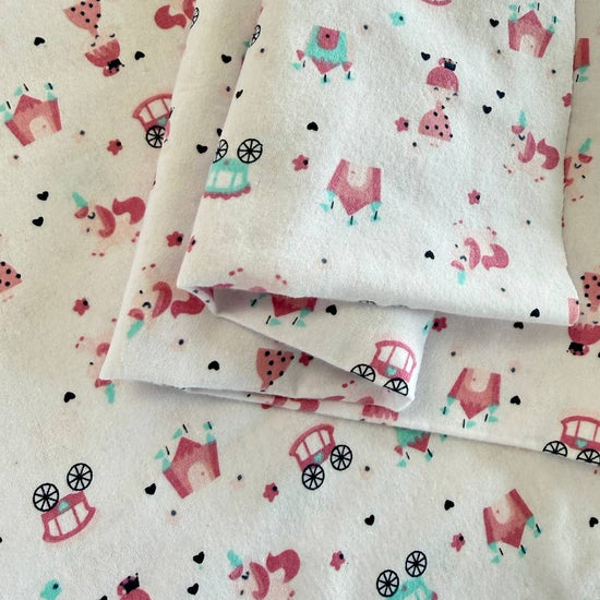 Soft white flannelette fabric featuring pink princesses, unicorns, castles, carriages, dresses, and crowns in a whimsical fairytale print.
