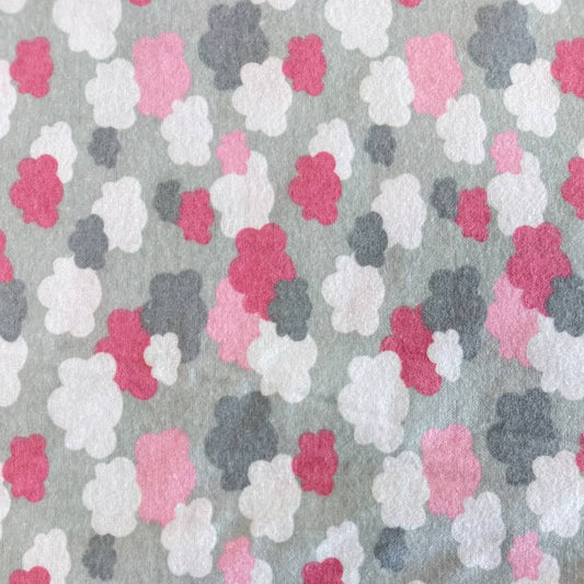 Soft flannelette fabric featuring pink, grey, and white cloud shapes on a light grey background in a playful nursery-inspired pattern.