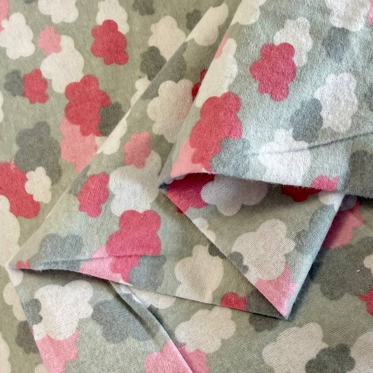 Soft flannelette fabric featuring pink, grey, and white cloud shapes on a light grey background in a playful nursery-inspired pattern.
