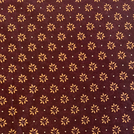 Wheatland quilting cotton fabric by Kansas Troubles Quilters for Moda Fabrics featuring a small repeating floral motif in warm beige tones on a rich mulberry background.